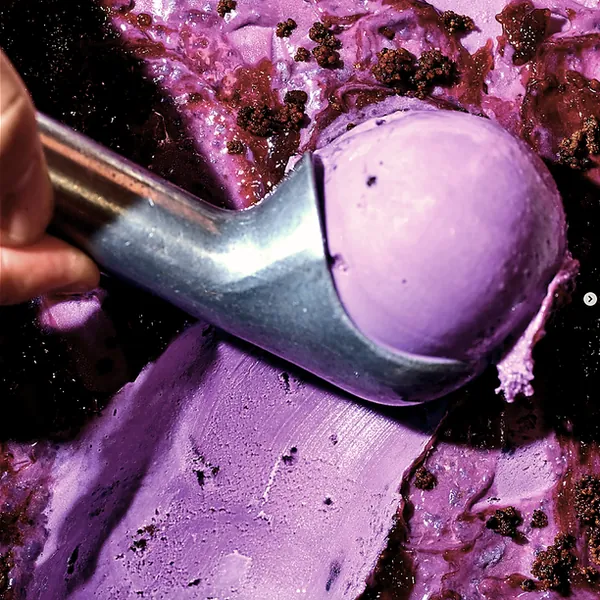 A scoop being drawn through purple ube gelato